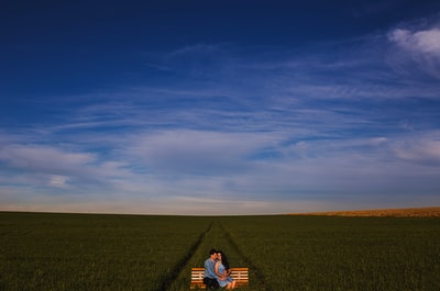 两个男人和女人坐在草地上的长凳上的照片
